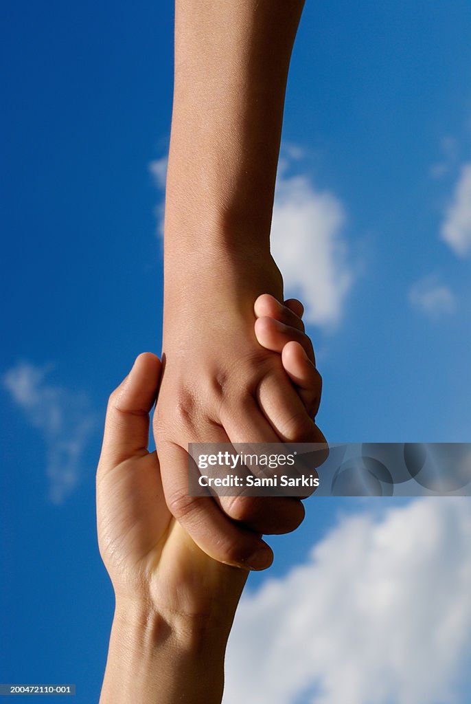 Two children (9-13) holding hands, close-up
