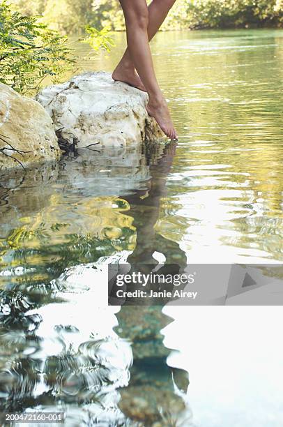 young woman standing on rock, dipping toes in river,  low section - dips stock pictures, royalty-free photos & images