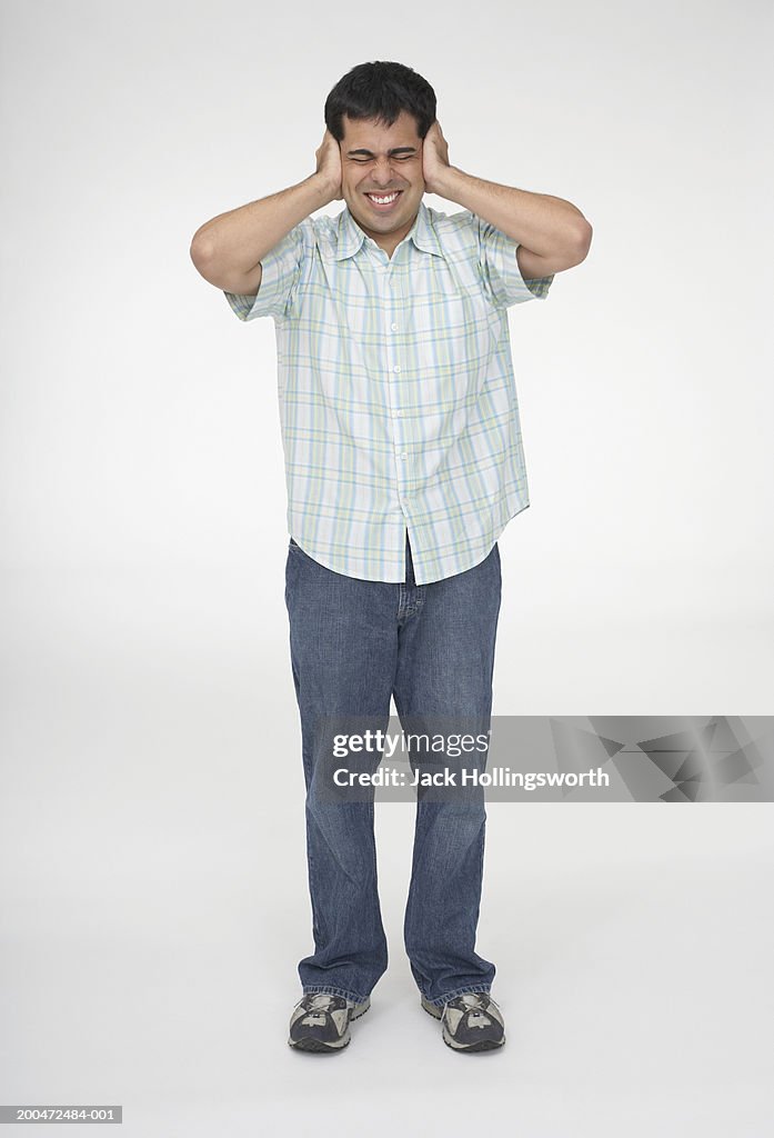 Mid adult man covering his ears with his hands