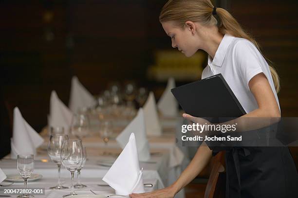 young waitress adjusting table settings in restaurant, side view - table dressée photos et images de collection