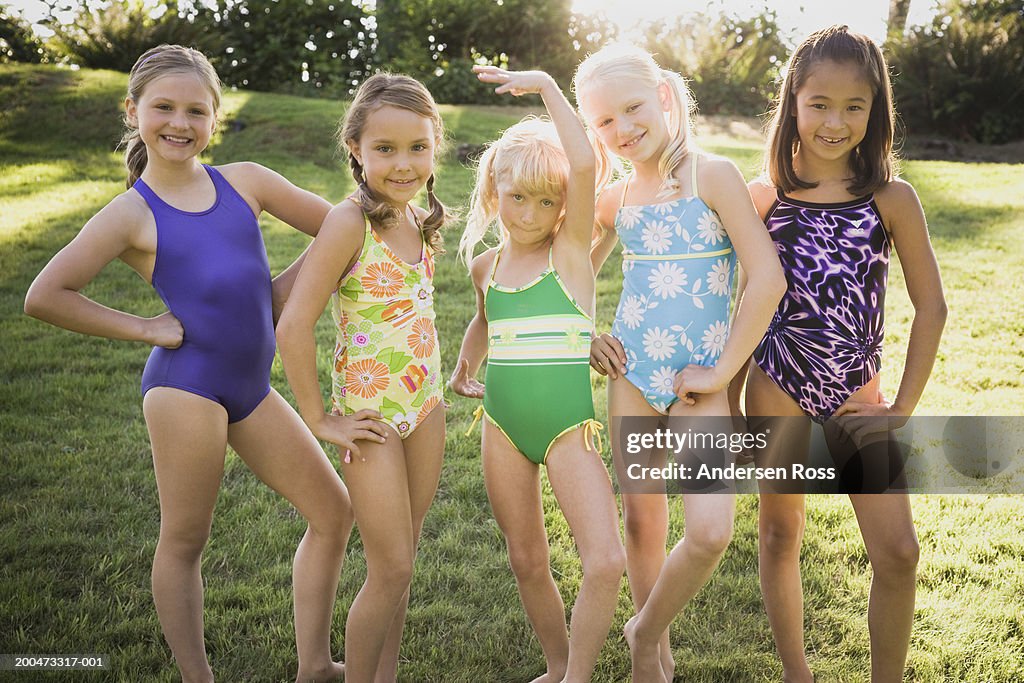 Five girls (7-10) in swimsuits standing side by side, portrait