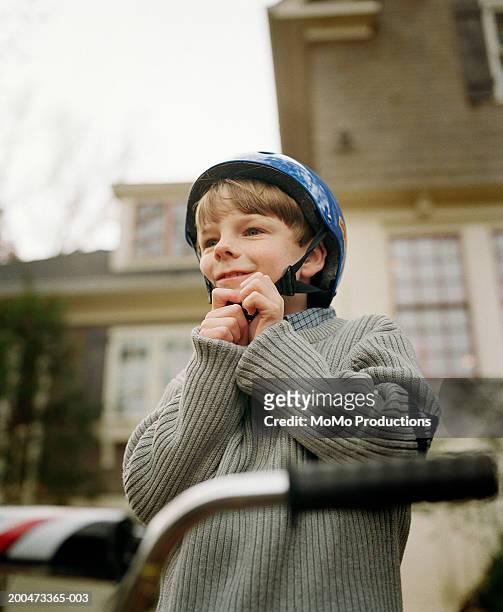 boy (6-8) on bicycle fastening safety helmet - abrochar fotografías e imágenes de stock