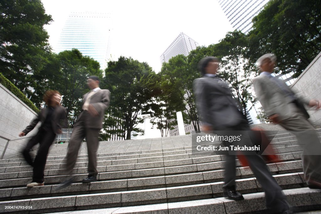 Four executives walking down stairway, low angle view (blurred motion)