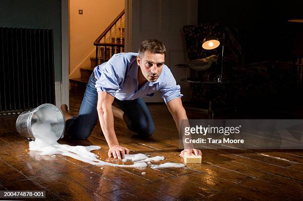young man scrubbing wooden floor with sponge - clean floor stock pictures, royalty-free photos & images
