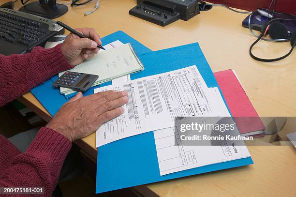 mature man preparing tax forms, close-up - hacienda fotografías e imágenes de stock