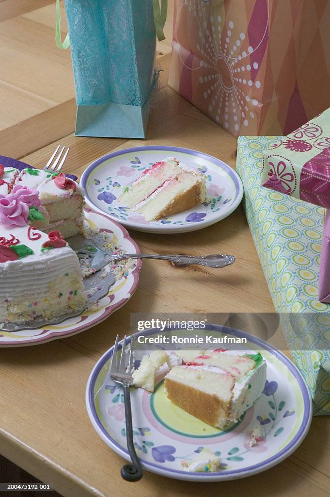 Slices of birthday cake and present on table