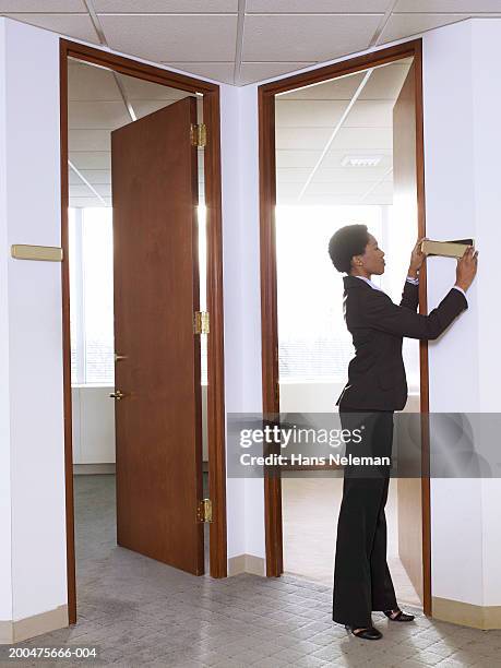 businesswoman putting nameplate on wall in empty office, side view - nameplate stock-fotos und bilder