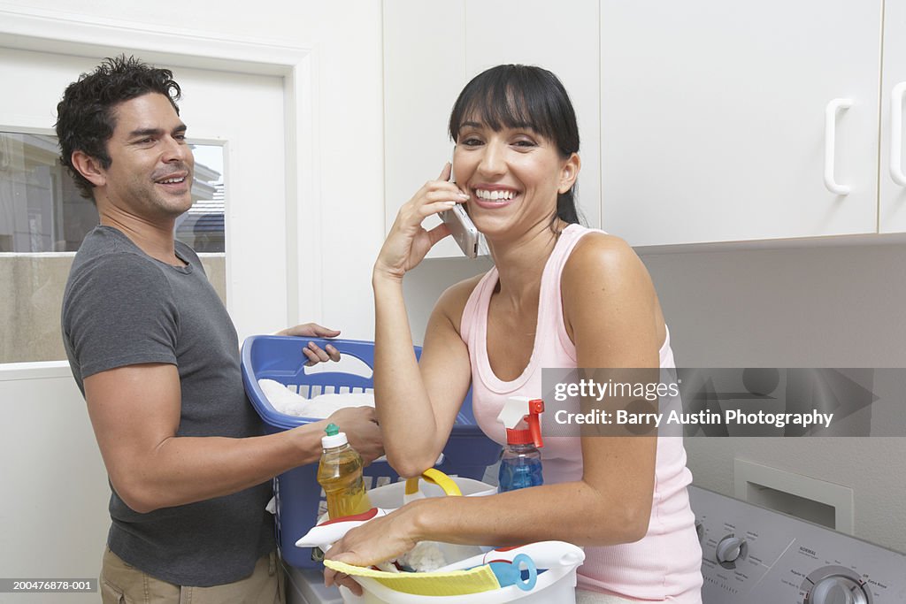 Couple in utility room, woman using mobile phone, smiling, portrait