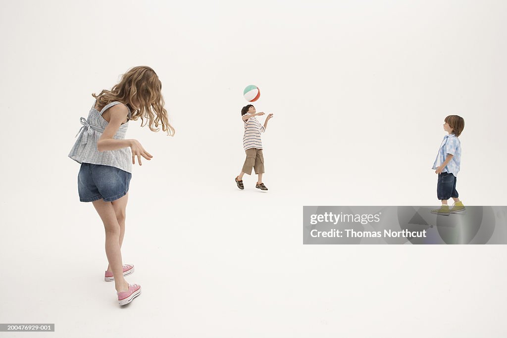 Three siblings (7-11) playing with beach ball