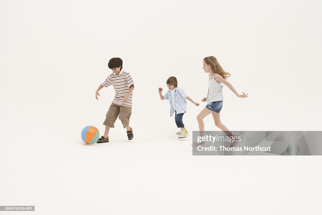 Three siblings (7-11) playing with beach ball