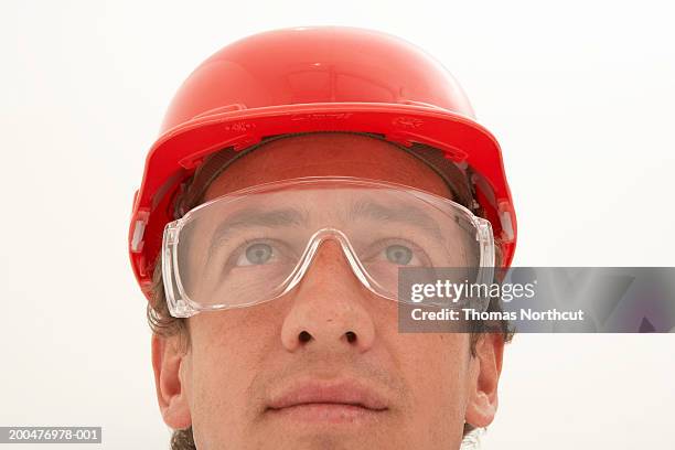 man wearing protective eyewear and hard hat, looking up - construction worker on white stock pictures, royalty-free photos & images