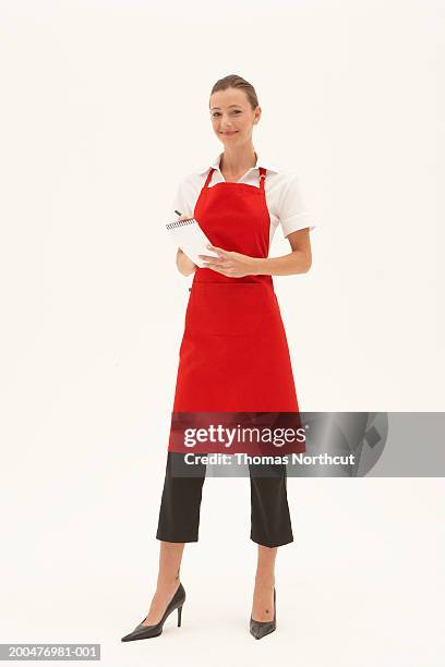 young waitress writing order on notepad, smiling, portrait - grembiule foto e immagini stock