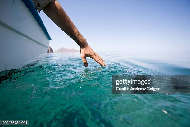 man touching water from boat - boat on water stock-fotos und bilder