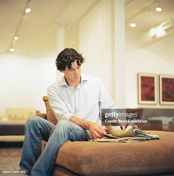 man sitting on ottaman stool looking at fabric swatches - fabric swatches imagens e fotografias de stock
