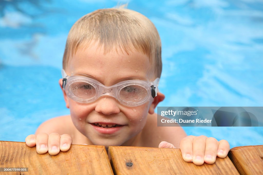 Boy (4-6) in swimming pool wearing goggles, portrait