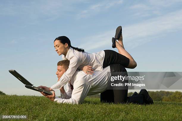 businesswoman on man's back, both using same laptop - bending over in skirt stock-fotos und bilder