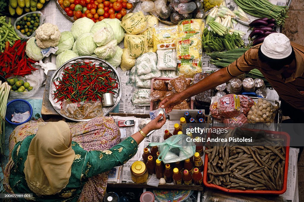 Man buying produce from woman at market, elevated view