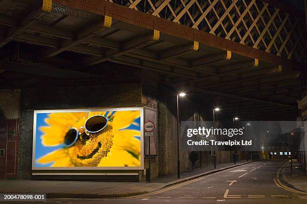 smiling sunflower on billboard beside dark road - insegna commerciale foto e immagini stock