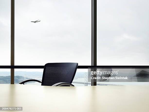 empty desk, commercial plane flying in background (digital composite) - leerer schreibtisch stock-fotos und bilder