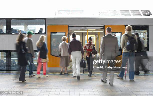 "commuters on platform boarding train, rear view (blurred motion)" - binario di stazione ferroviaria foto e immagini stock