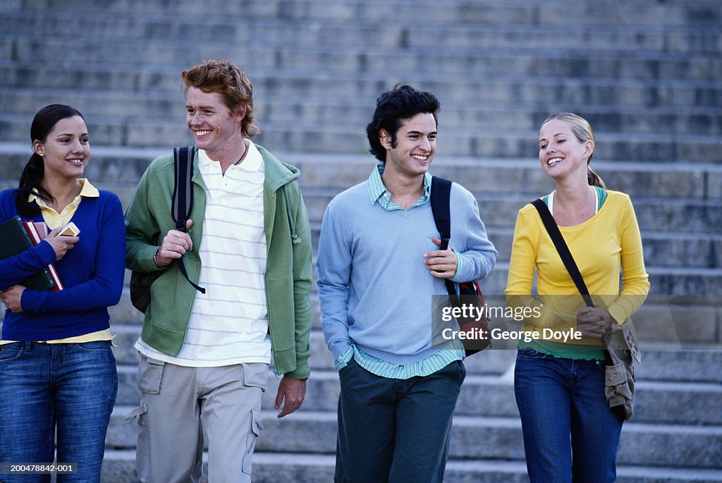 Four male and female students walking in row, smiling