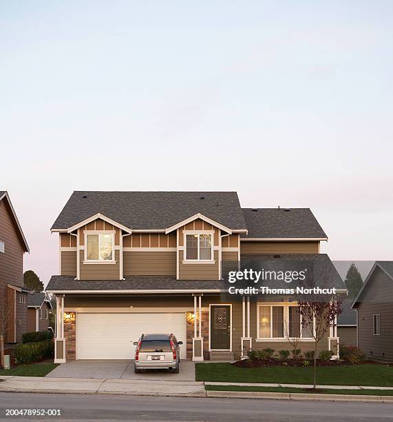 exterior of house with car parked in driveway, sunset - stationary stock-fotos und bilder