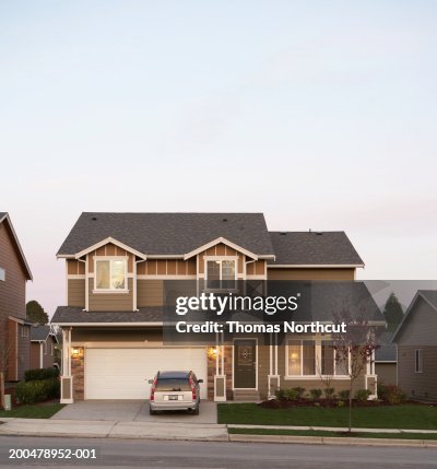 Exterior of house with car parked in driveway, sunset Exterior of house with car parked in driveway, sunset