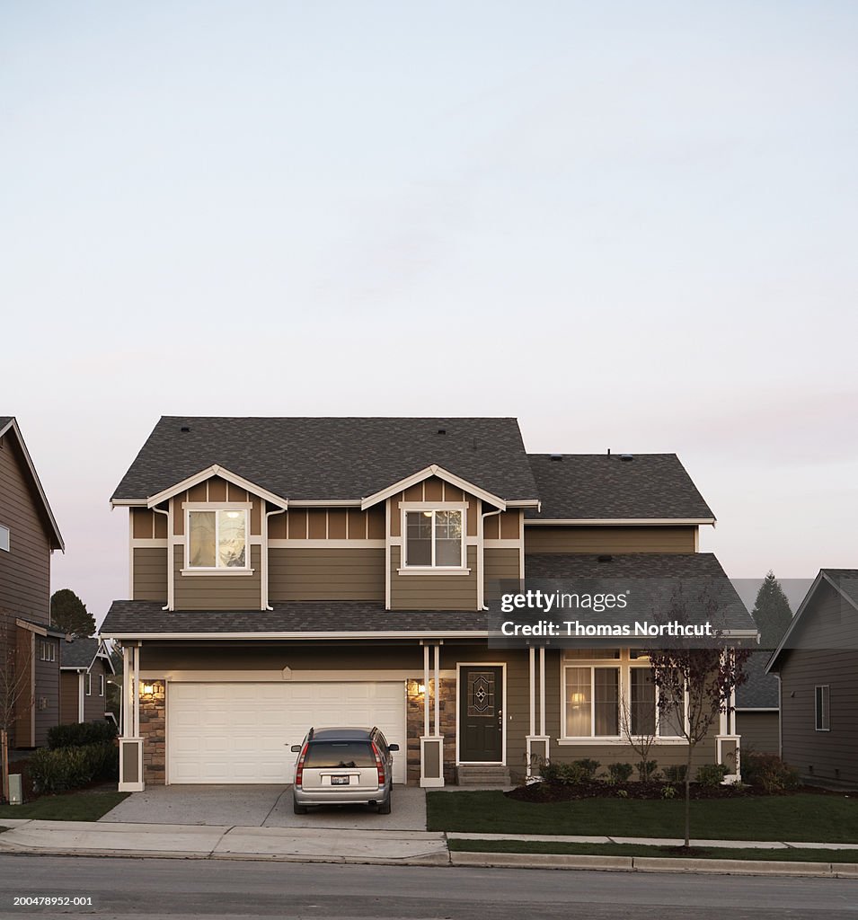 Exterior of house with car parked in driveway, sunset