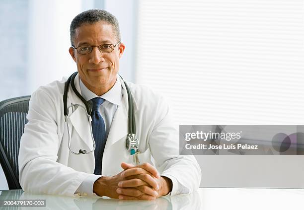 mature doctor smiling, portrait - doctor desk stock pictures, royalty-free photos & images