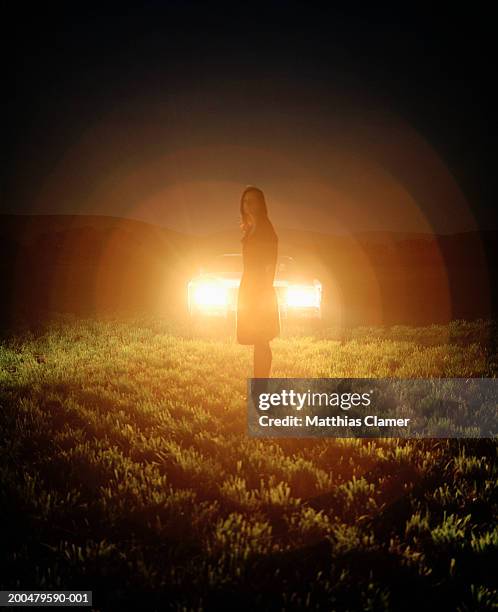 young woman caught in car's headlights, night - car lights stock pictures, royalty-free photos & images