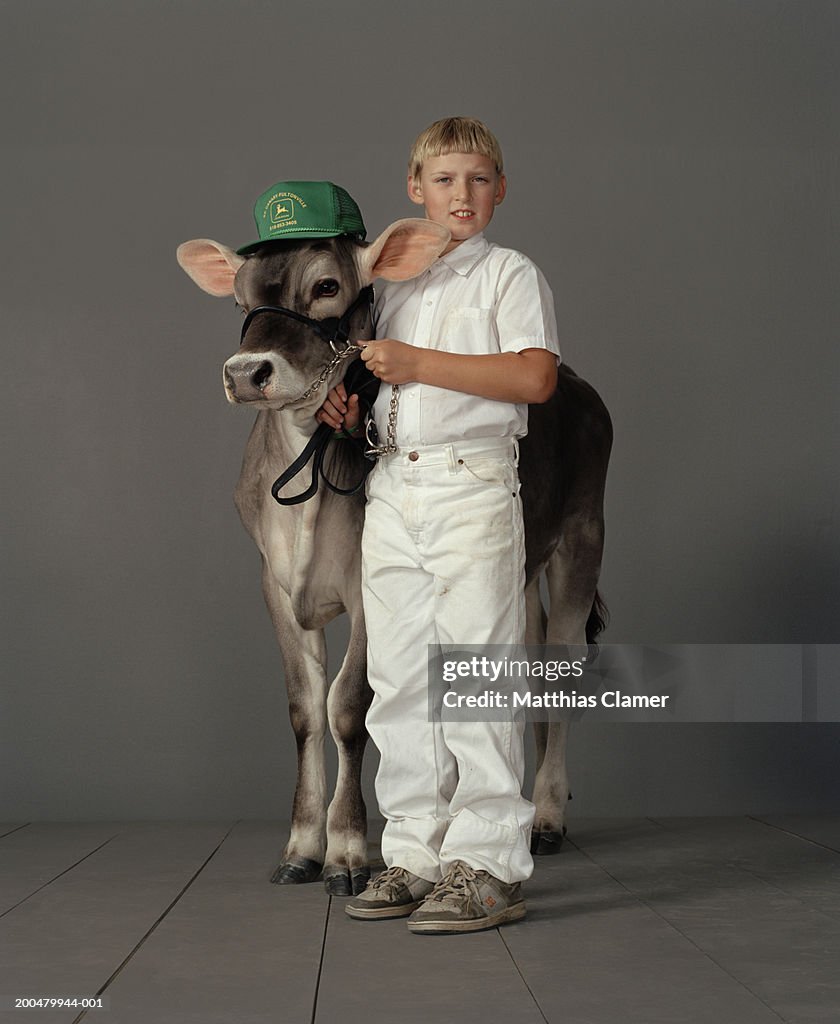 Boy (8-10) dressed in white with prize cow wearing cap, portrait