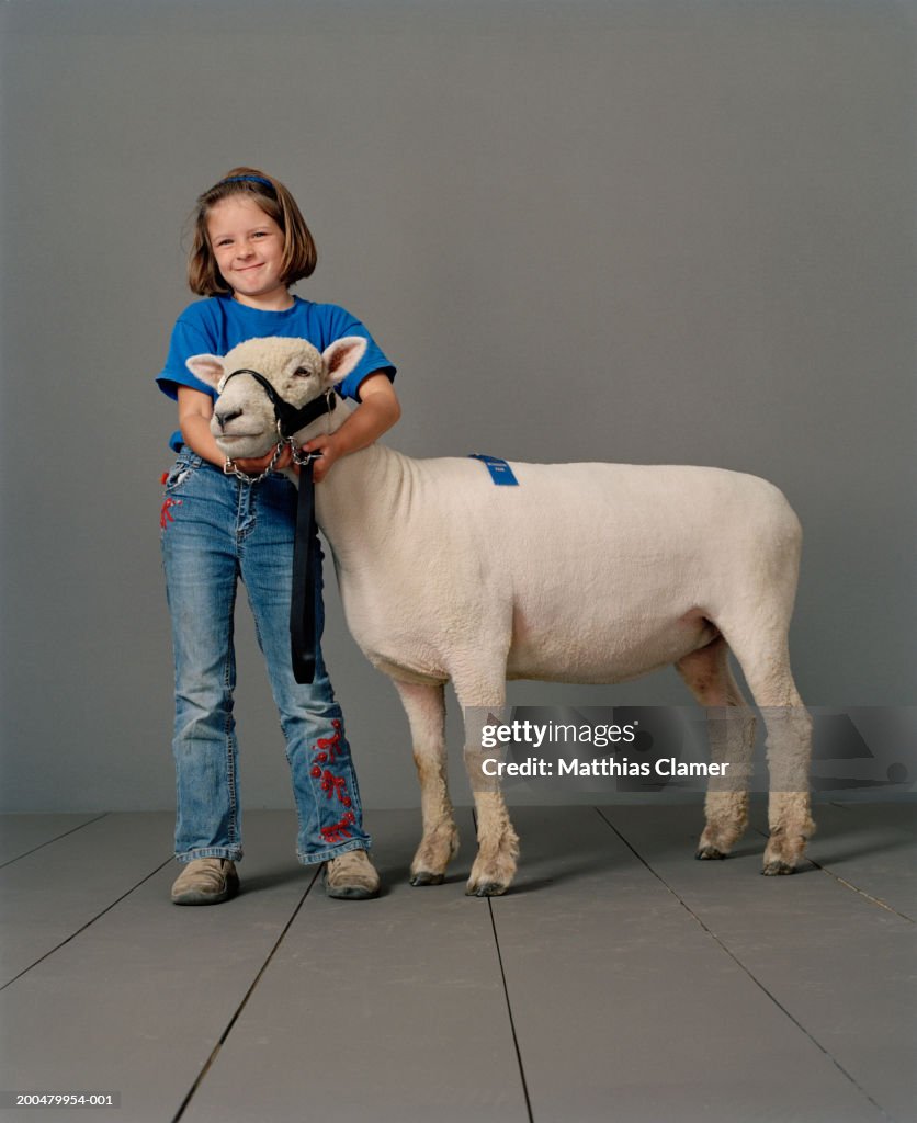 Girl (6-8) with sheep, portrait