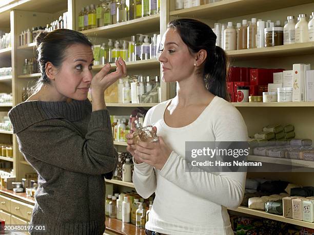 woman with sales clerk sampling perfume - perfumería fotografías e imágenes de stock