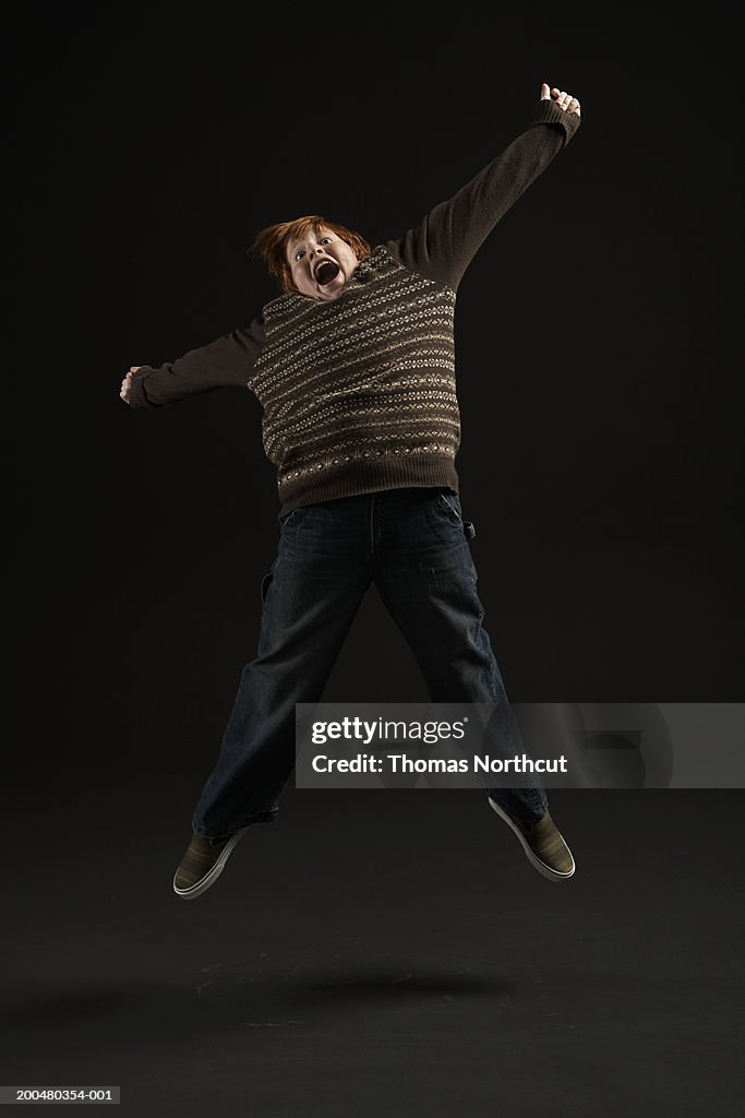 Boy (11-13) jumping in midair, arms outstretched