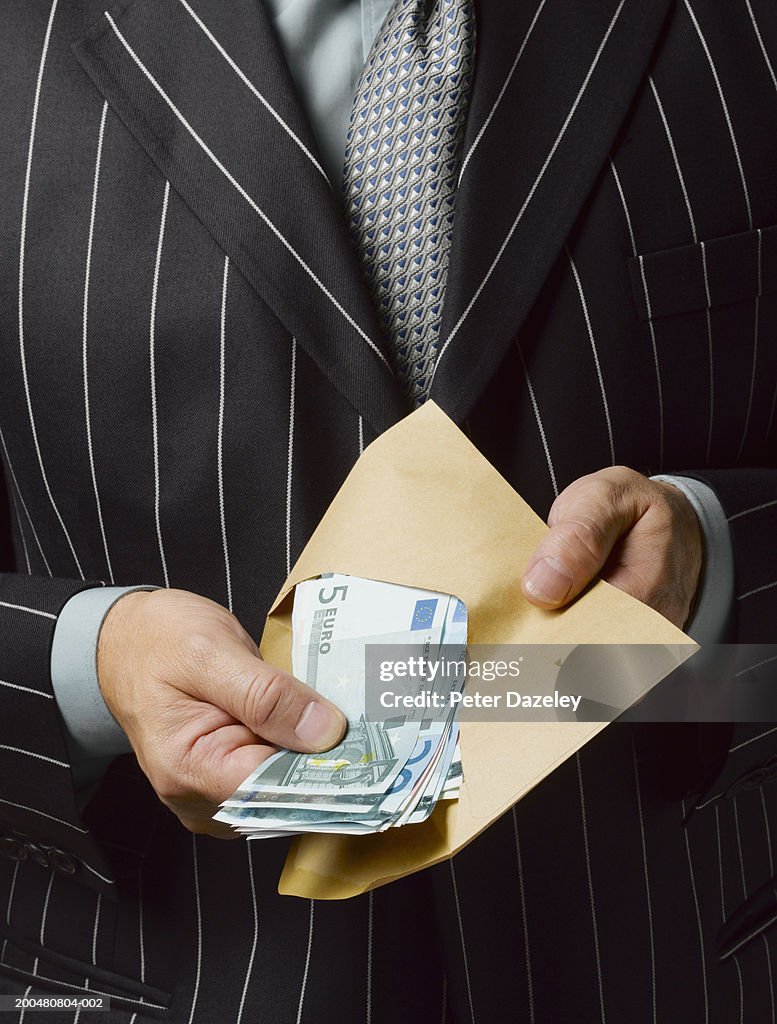 Businessman holding envelope of Euro notes, close-up, mid section