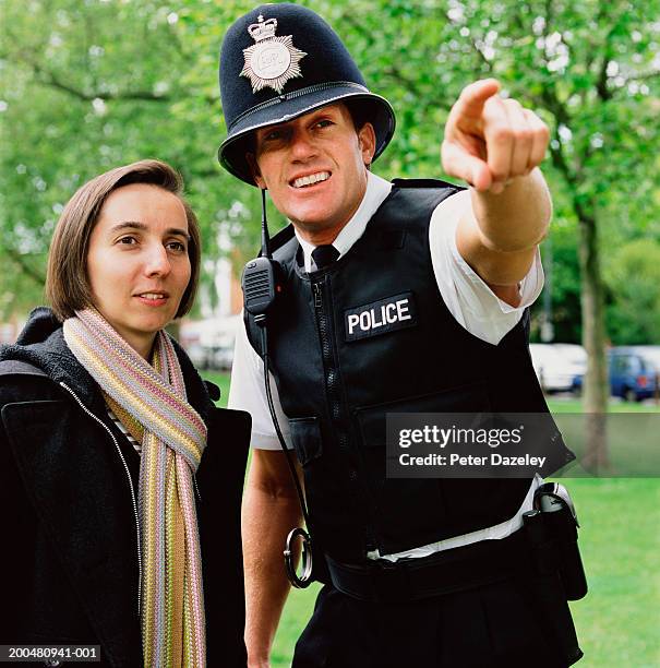 policeman pointing beside woman - police officer uk stock pictures, royalty-free photos & images