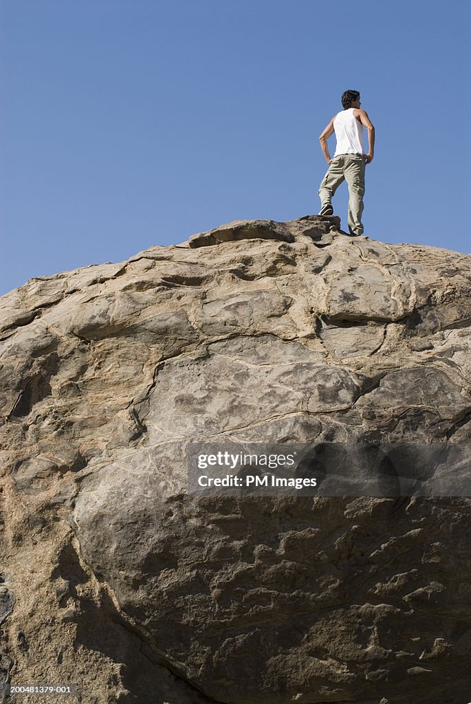 Young man standing on rock, low angle view