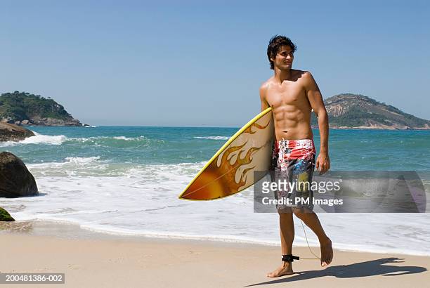 young man with surfboard walking on beach - beach hold surfboard stock-fotos und bilder