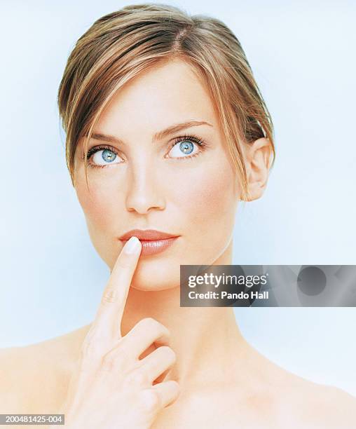young woman with finger on lip, looking up, close-up - finger studio close up ストックフォトと画像