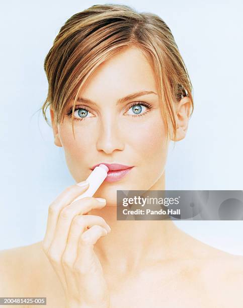 young woman applying lip balm, close-up, portrait - lip balm stock pictures, royalty-free photos & images