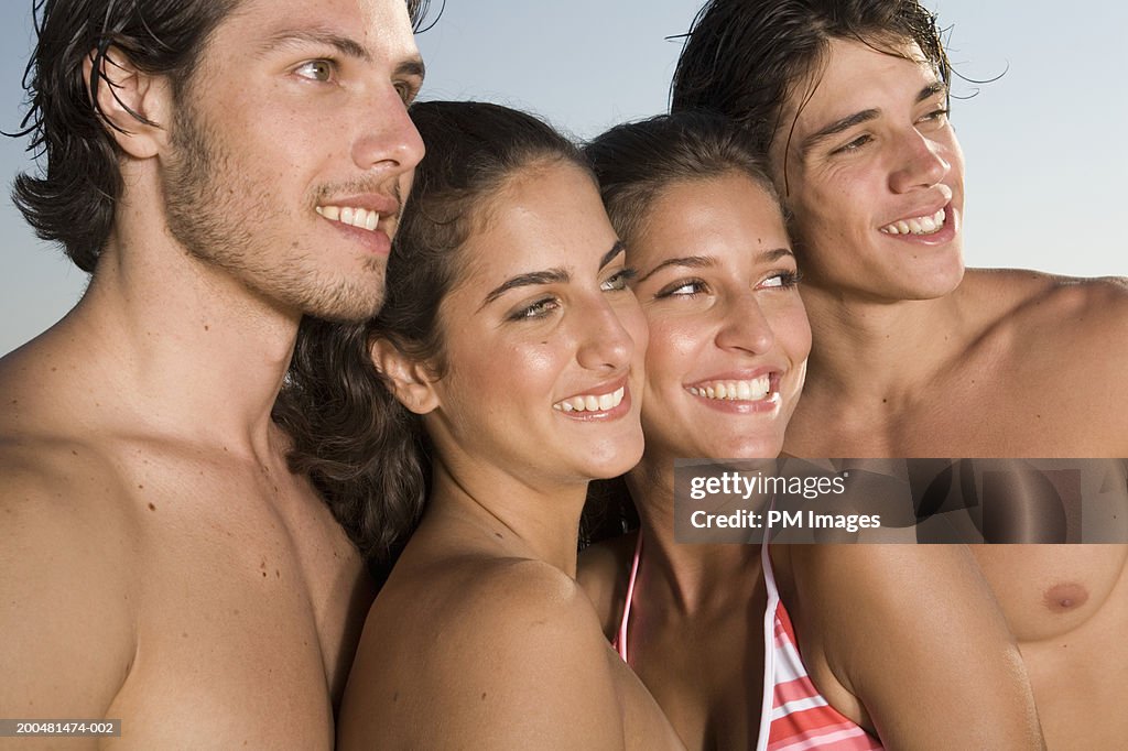 Two young couples at beach looking to side
