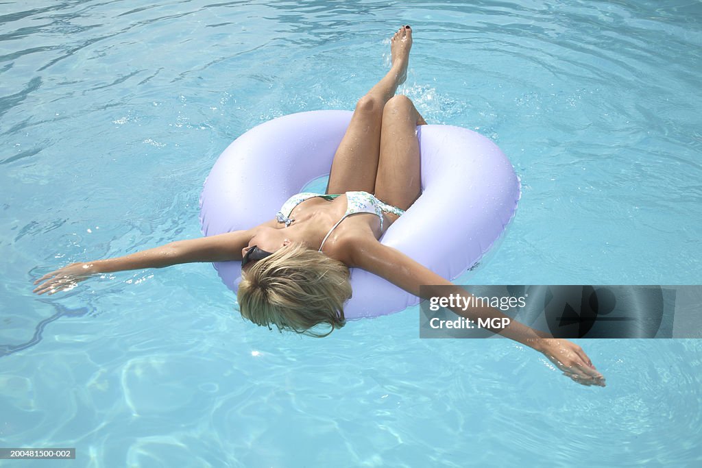 Young woman floating in pool, elevated view