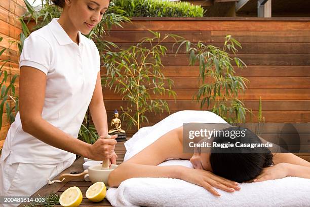 spa attendant beside young woman on massage table - balneario fotografías e imágenes de stock