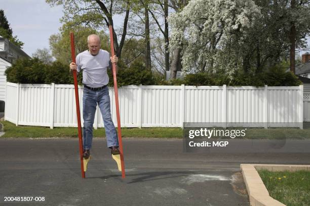 senior man walking on stilts - stilts stock pictures, royalty-free photos & images
