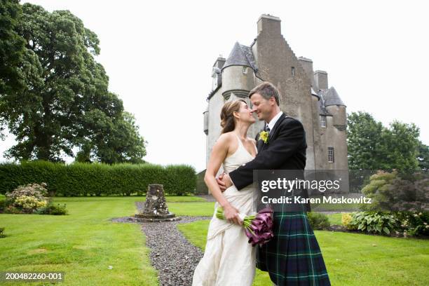 bride and groom kissing on footpath in garden, castle in background - castle scotland woman stockfoto's en -beelden