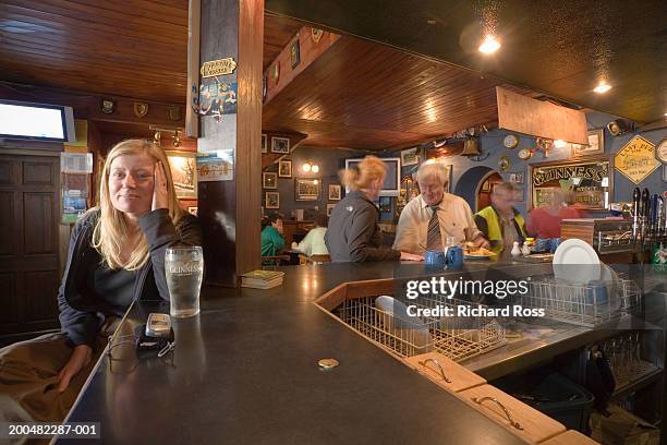 woman sitting at counter in bar - irish pub fotografías e imágenes de stock