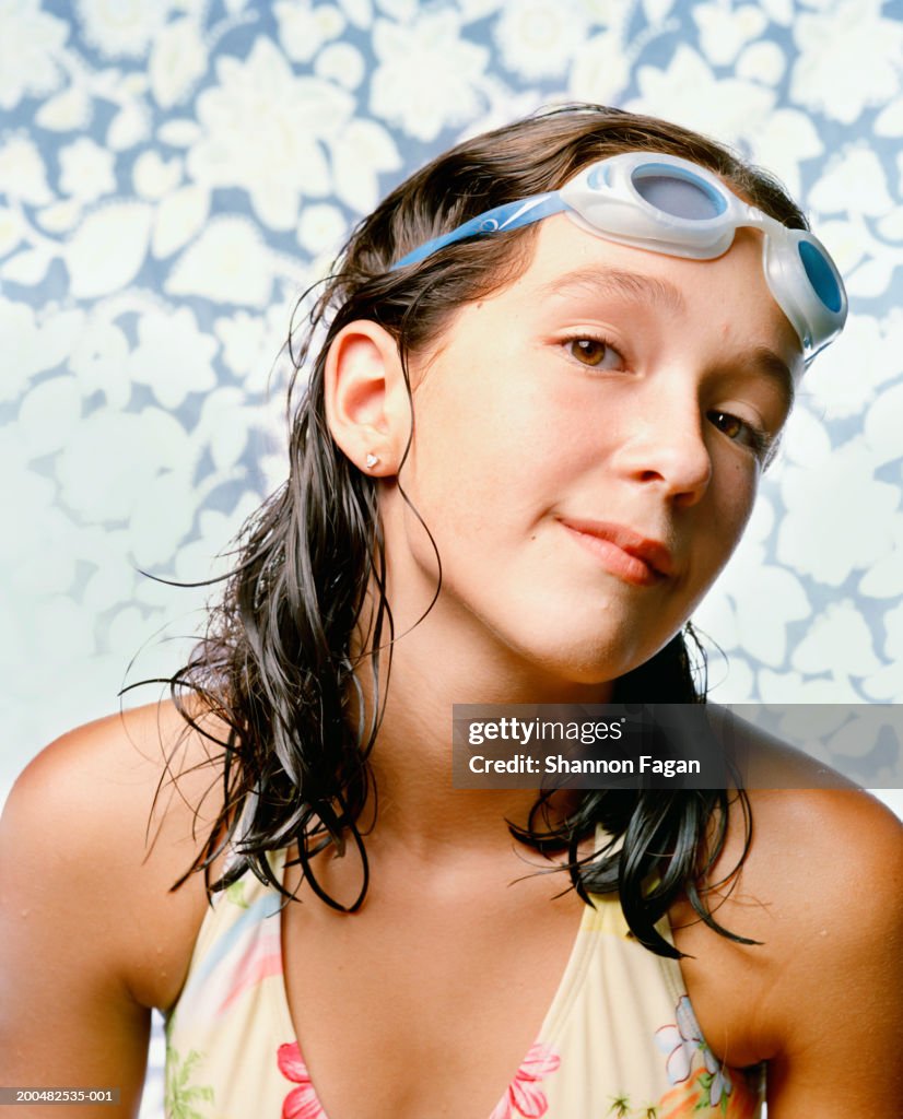 Girl (10-11) wearing swimming costume and goggles, portrait