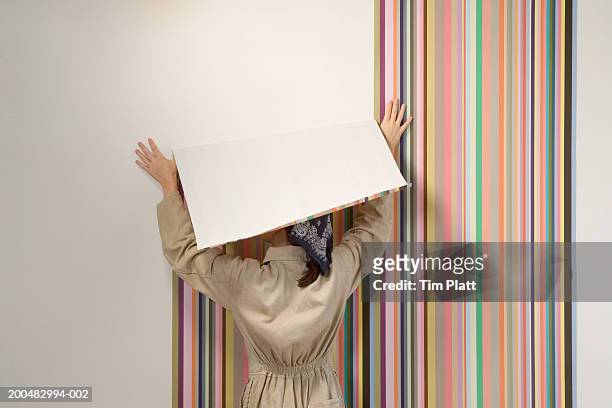 woman hanging wallpaper, rear view - vrouw behangen stockfoto's en -beelden