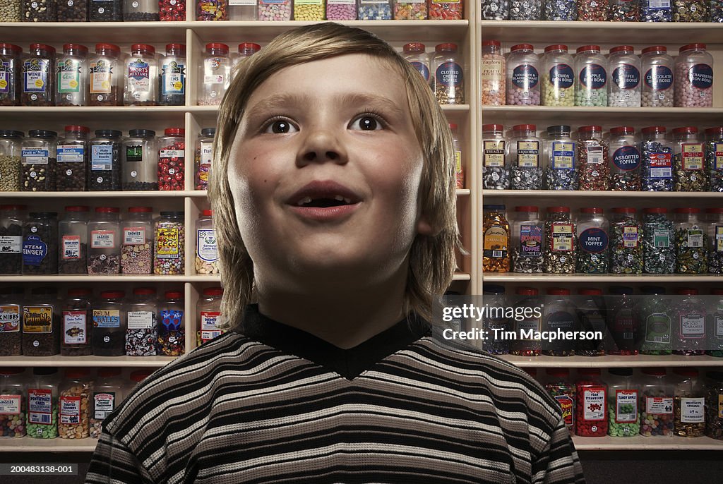 Boy (6-8) in sweetshop, close-up (Digital Composite)