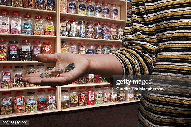 boy (6-8) in sweetshop, holding out palm with loose change, close-up (digital composite) - candy jar stock pictures, royalty-free photos & images